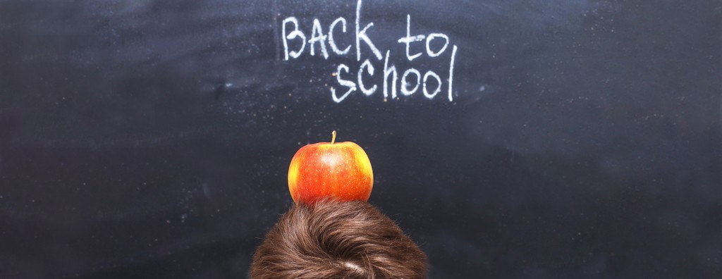 un tableau noir avec marqué "back to school" et on voit le haut d'une tete avec une pomme dessus